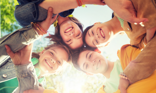 Lachende Kindergesichter im Kreis von unten fotografiert