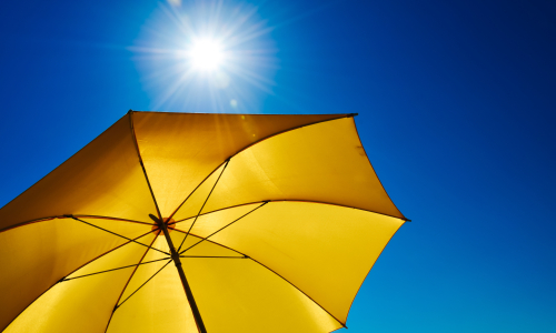 Ein gelber Sonnenschirm vor einem blauen Himmel