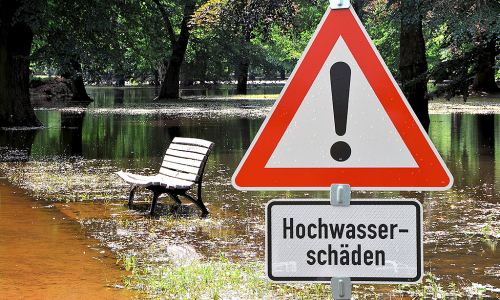 Überschwemmter Bereich mit einem Hinweisschild "Hochwasserschäden"