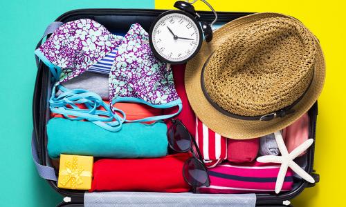 Offener, gefüllter Reisekoffer mit Urlaubskleidung und anderen Gegenständen
