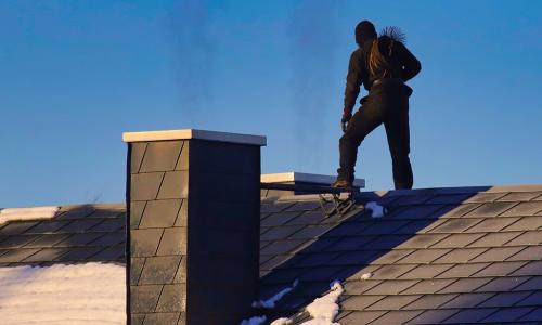 Schornsteinfeger arbeitet auf einem Dach