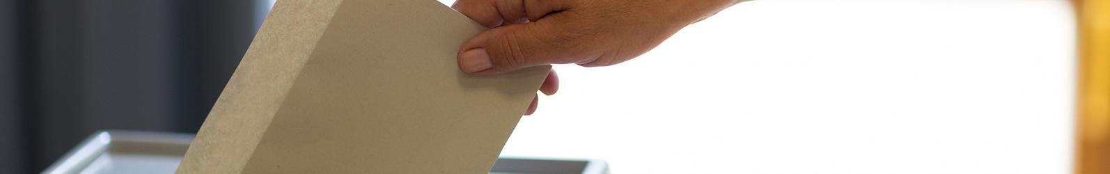 Stimmzettel wird in eine Wahlurne geworfen