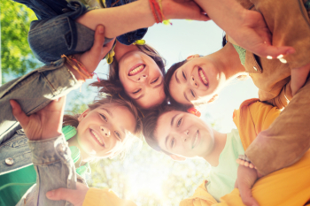 Lachende Kindergesichter im Kreis von unten fotografiert