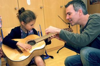 Gitarrenlehrer unterrichtet kleines Mädchen