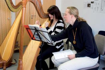 Lehrerin unterrichtet Frau an der Harfe