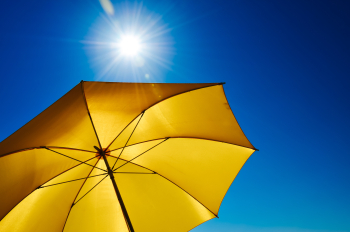 Ein gelber Sonnenschirm vor einem blauen Himmel