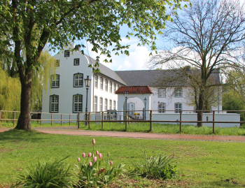 weiße Burg umgeben von Bäumen und Wiesen