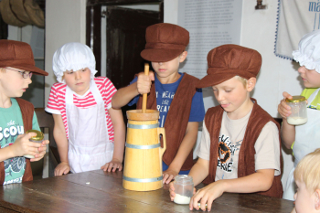 Kinder in historischer Kleidung schlagen Butter